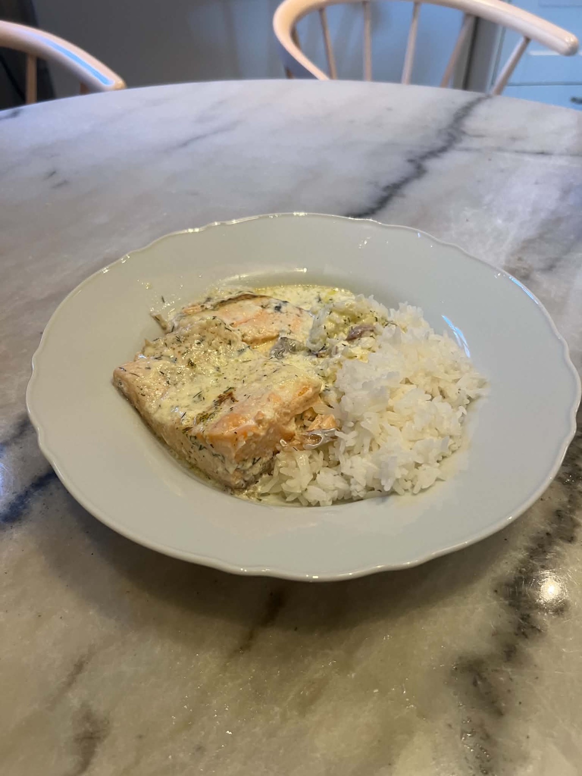 Lax i gräddsås serverad med ris på en djup tallrik