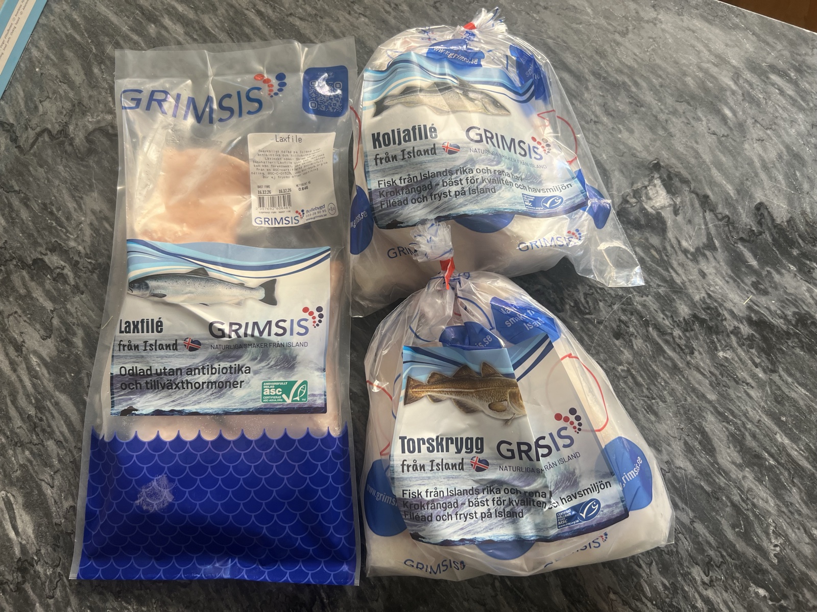 De tre Grimsis-produkterna i testet: laxfilé, torskrygg och koljafilé i originalförpackning på en köksbänk