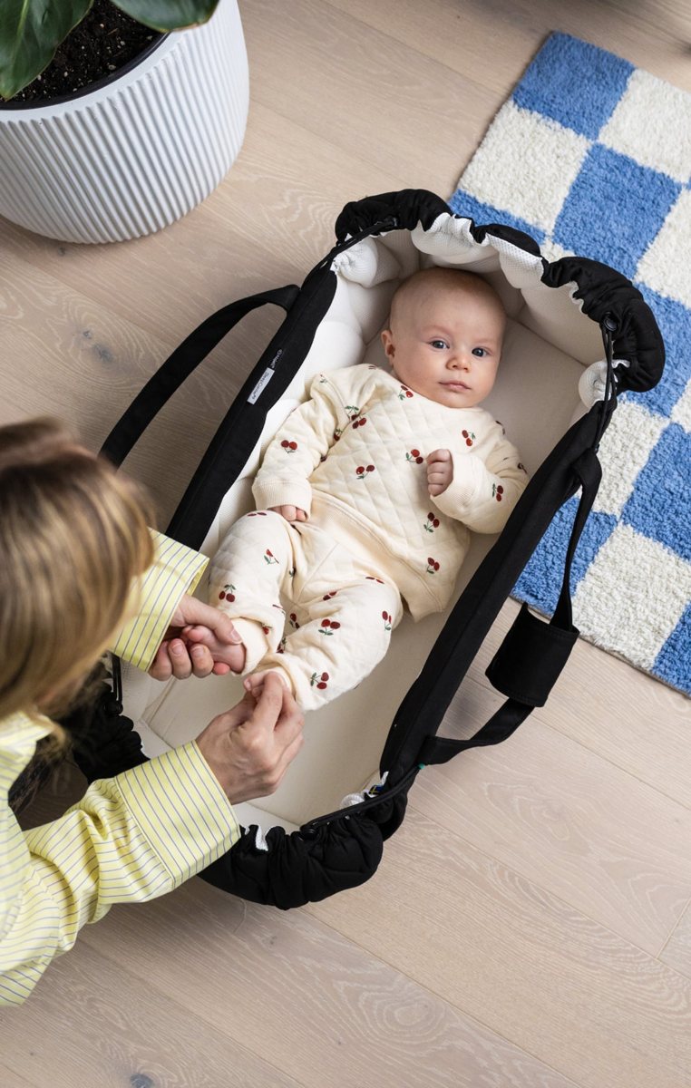 Bebis ligger i Najell SleepCarrier vol. 5 på golvet